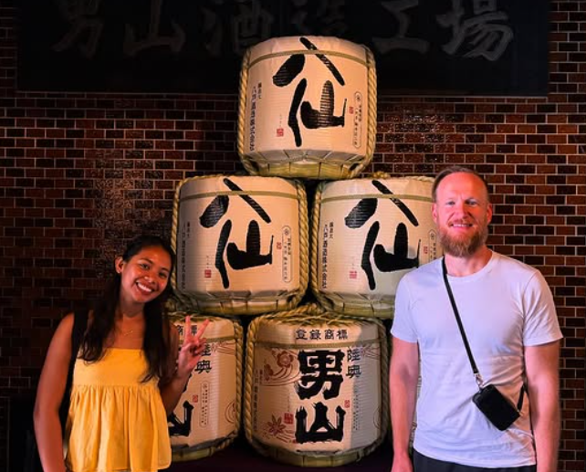 八戸酒造の酒樽の前に立つブライアンとジェシー
